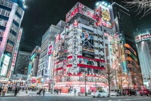 Explore the vibrant cityscape of Shinjuku, Tokyo at night with bright neon lights and bustling streets.