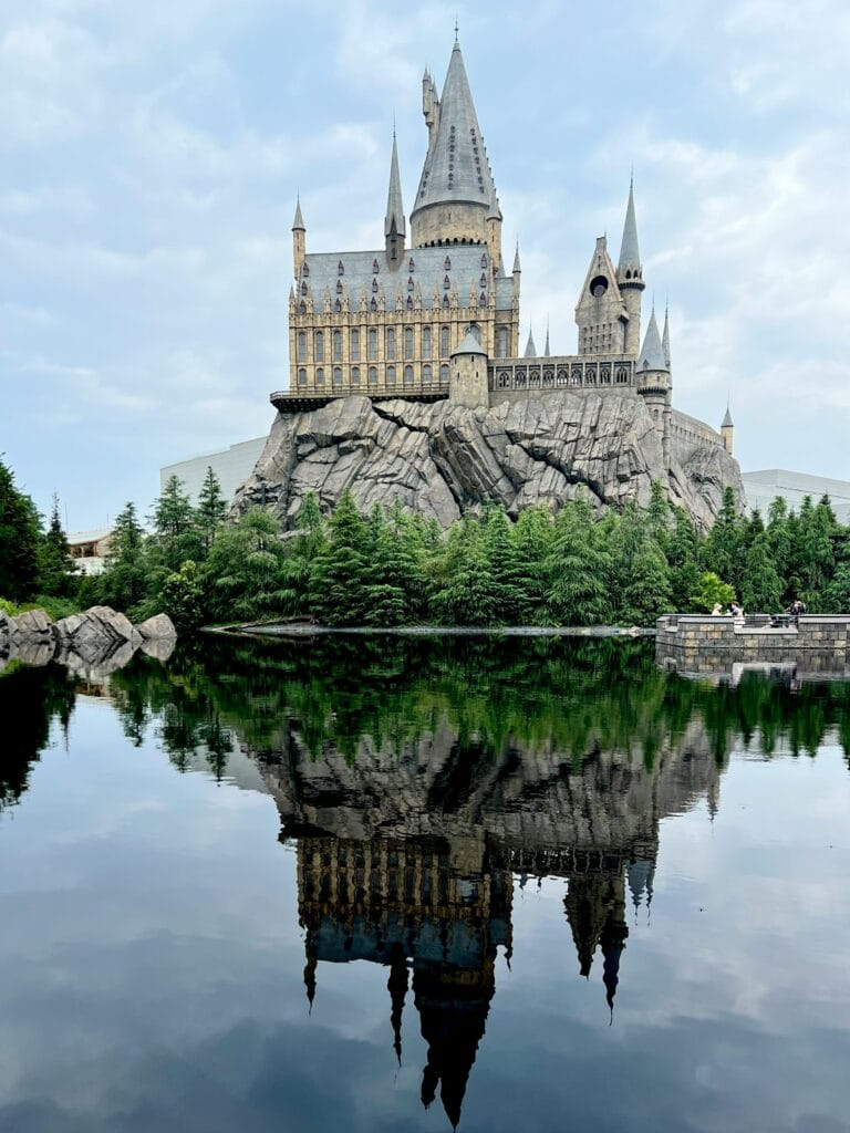 Stunning reflection of a fantasy castle in a serene lake at Osaka's theme park.