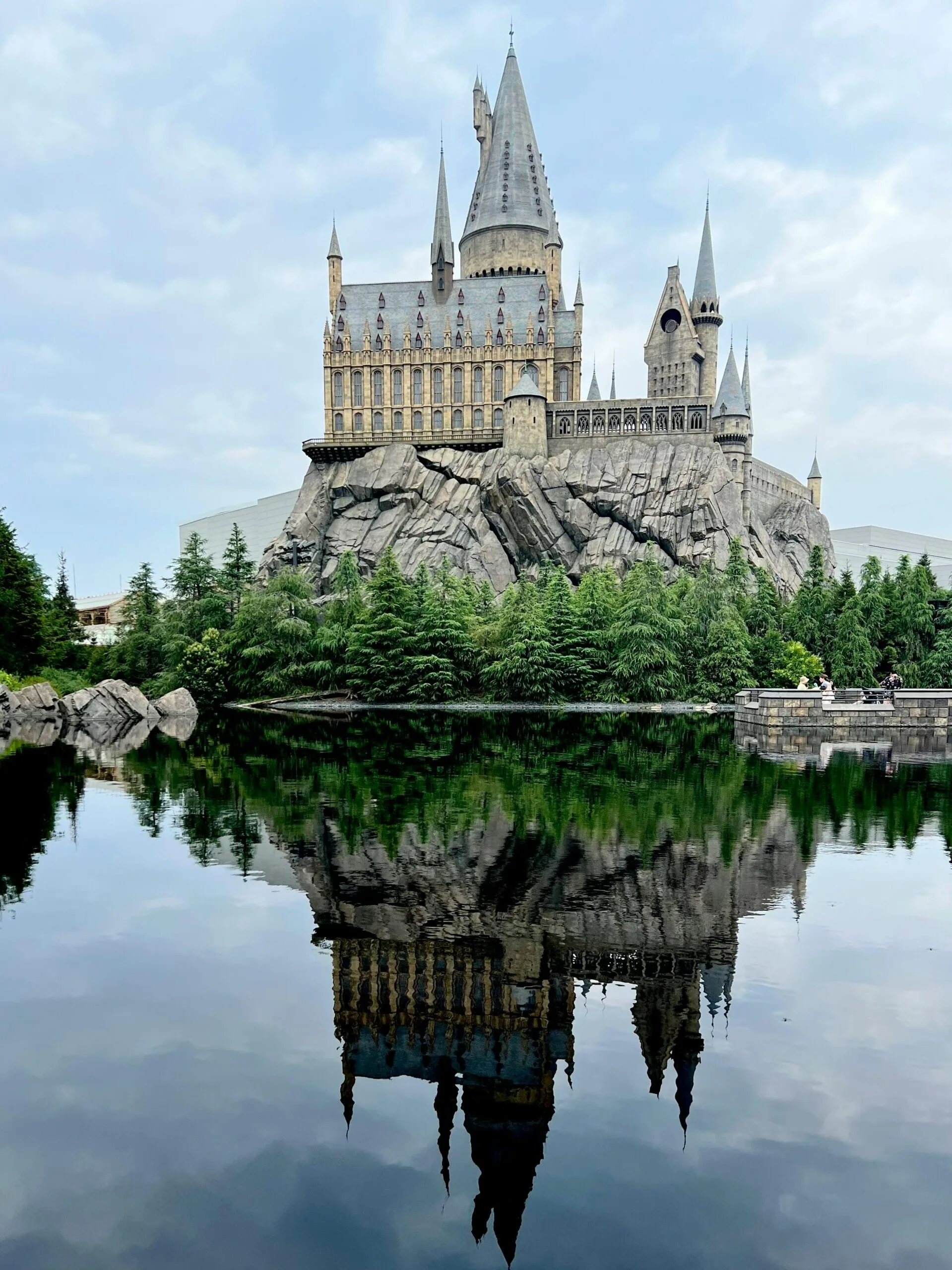 Stunning reflection of a fantasy castle in a serene lake at Osaka's theme park.