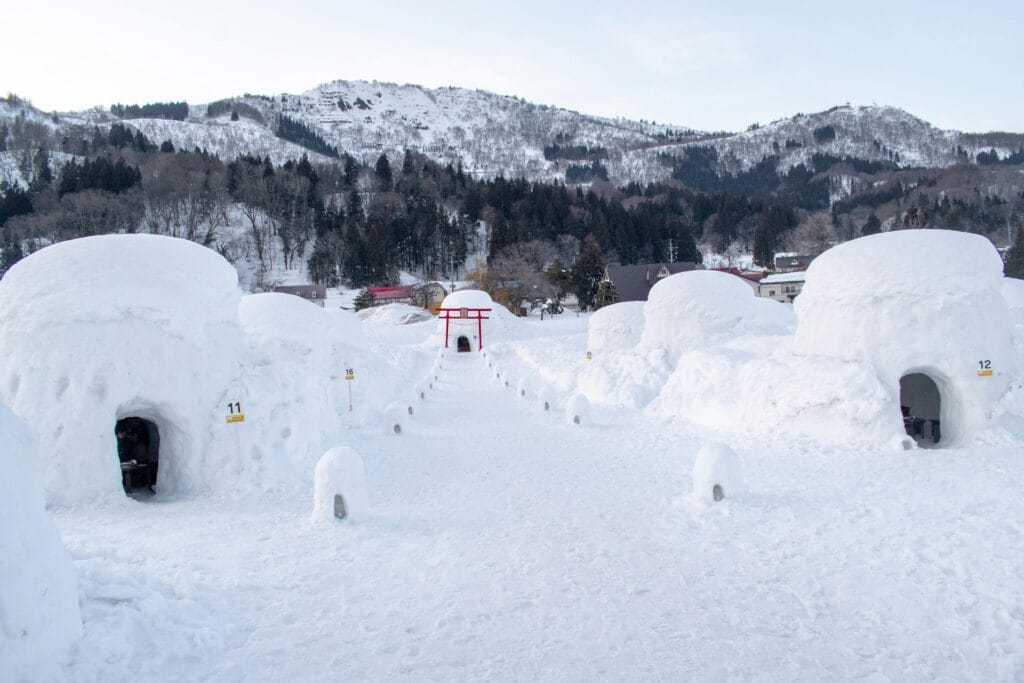 Traditional kamakura igloos in Iiyama, Nagano under a snowy landscape.