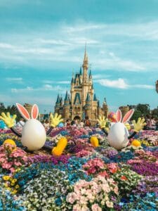Vibrant flowers and playful decorations adorn the iconic Tokyo Disneyland Castle in a festive springtime setting.