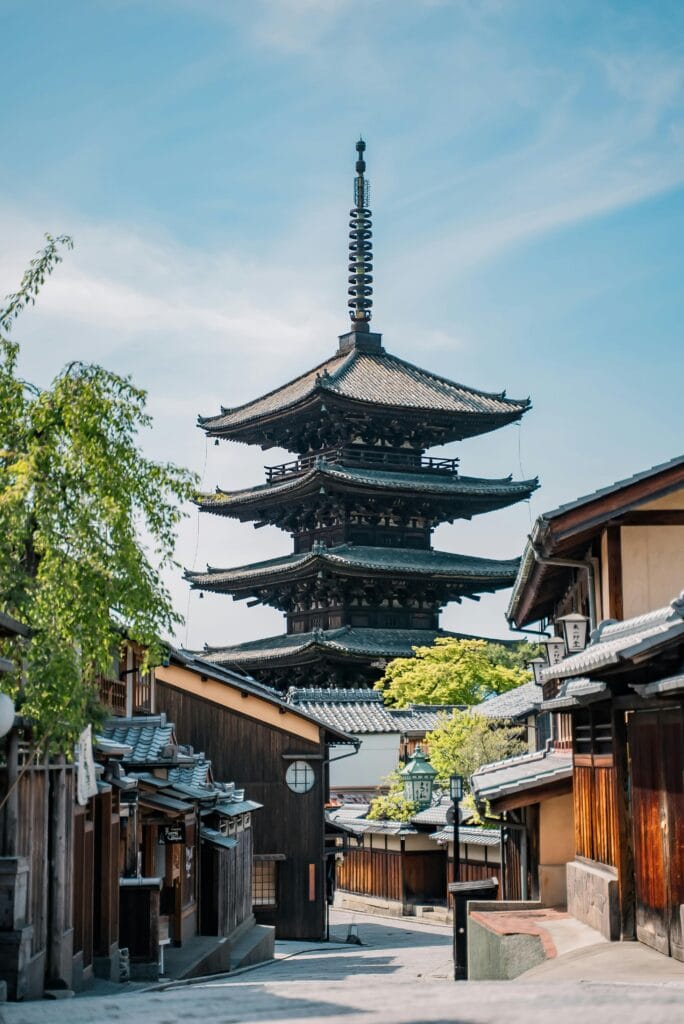 The iconic Yasaka Pagoda surrounded by traditional wooden houses in Kyoto, Japan, under a clear blue sky.