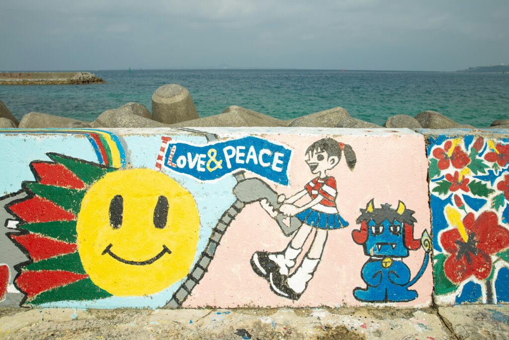 Okinawa on a Budget: Cheap Eats, Free Beaches & Smart Travel Tips Vibrant graffiti artwork on a seawall at Okinawa Beach, Japan with an ocean backdrop.